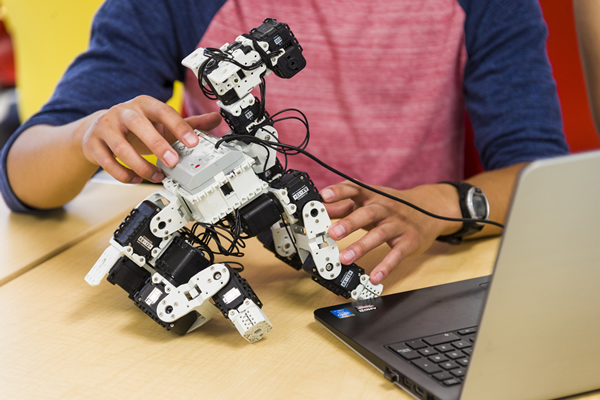 Student working with a modular robot next to a laptop
